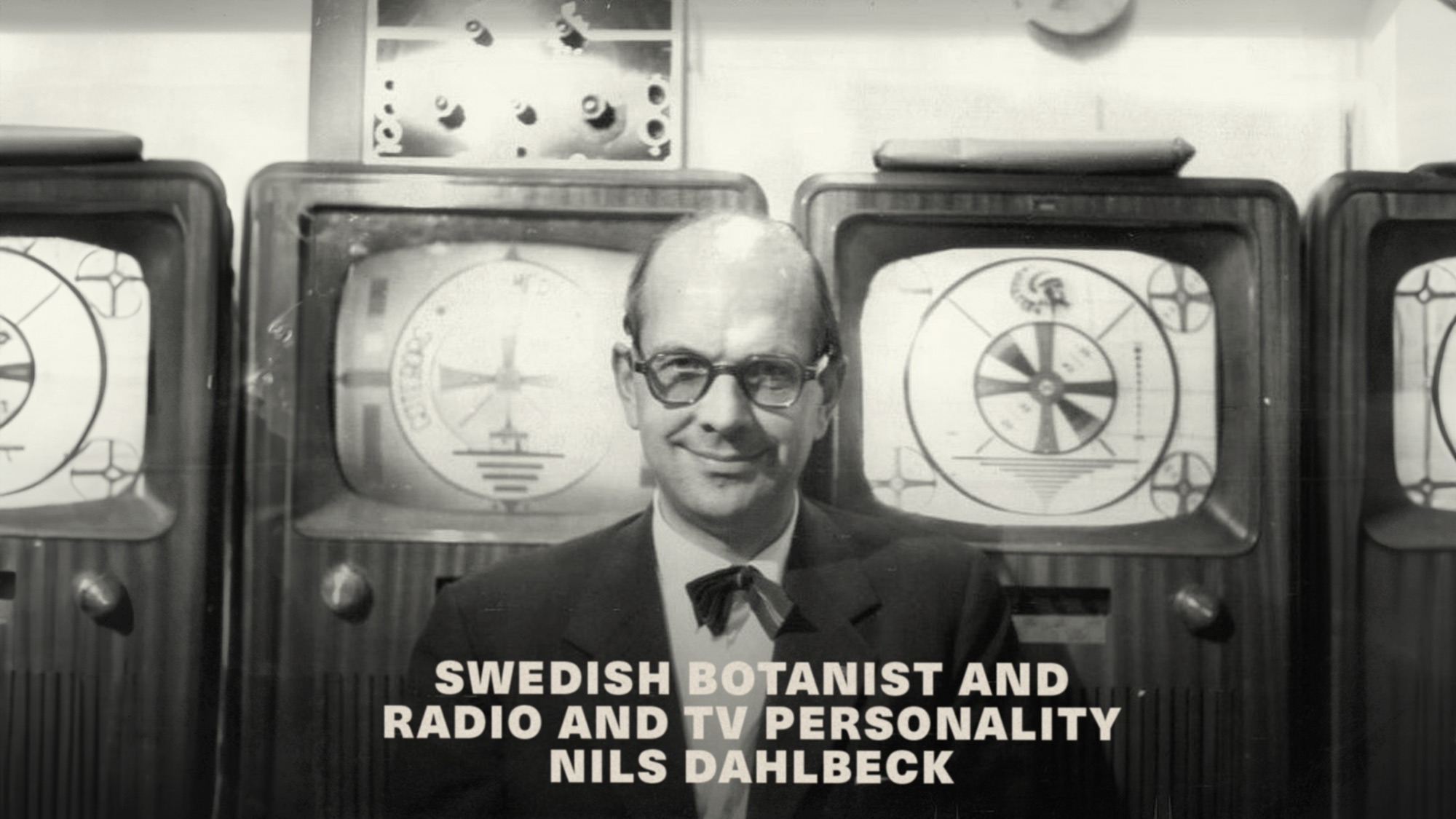 Swedish botanist and radio and TV personality Nils Dahlbeck posing in front of the Indian-head test pattern and the Chalmers University of Technology experimental TV station test card in 1957